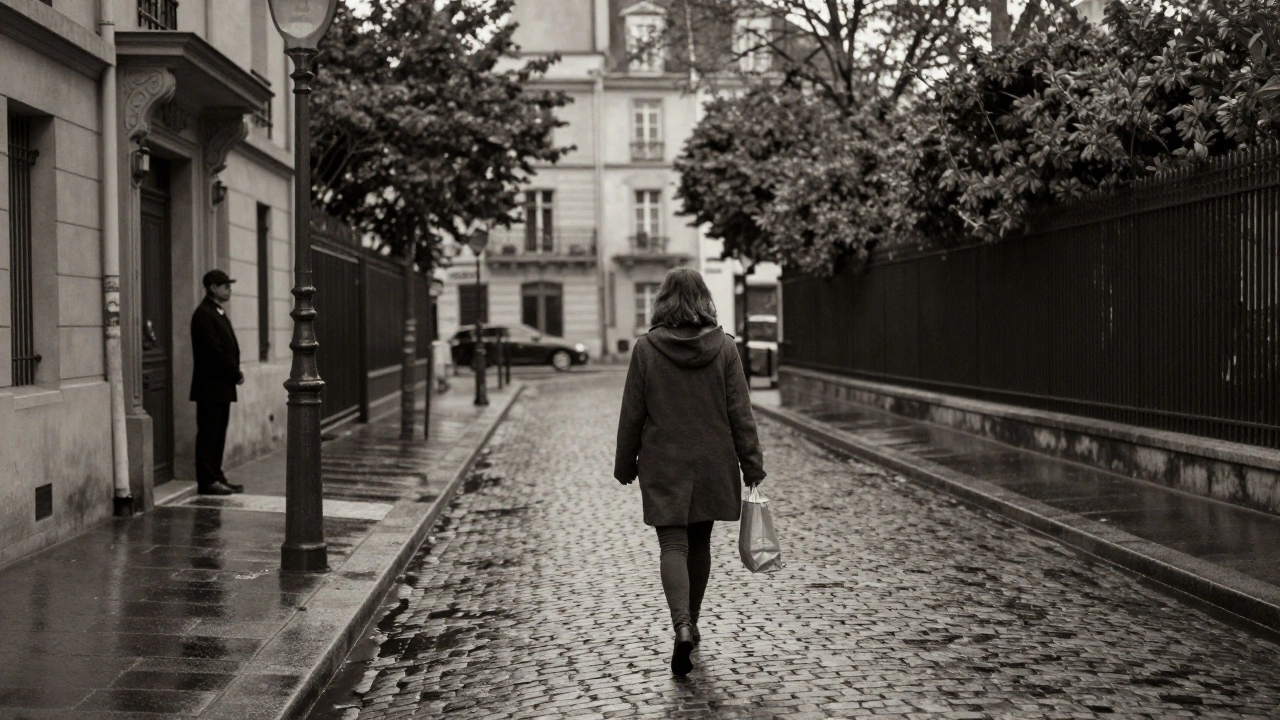 A woman walking alone down a rainy Paris street at twilight, coat over arm, quiet and dignified in the fading light.