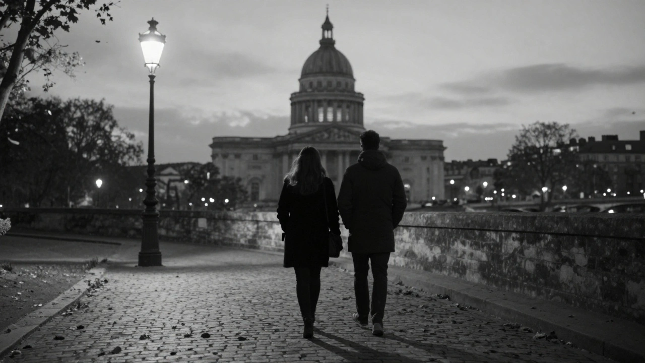 Silhouettes of a man and woman walking along the Seine near the Panthéon under historic streetlamps at dusk.