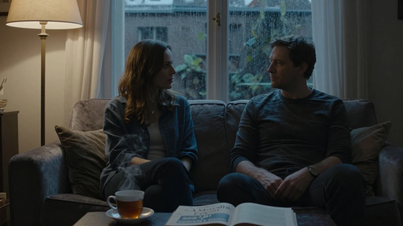 Two people sit side by side in a quiet Parisian apartment as rain falls on the window, tea and an open book on the table nearby.